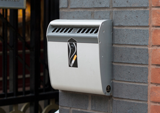 Ashmount™ Cigarette Bin which is wall mounted on the exterior of a residential housing block