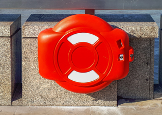 Guardian™ Lifebuoy Cabinet in red with white stickers against concrete building