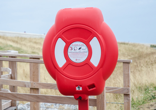 Guardian™ Lifebuoy Housing water safety equipment in red by seafront and sand dunes