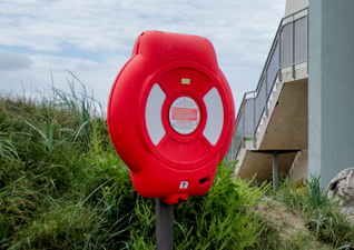 Guardian™ Lifebuoy Housings in red, post-mounted next to grassy area and outside stairs