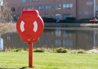 Guardian™ Lifebuoy Housing with Life Ring, post-mounted by lake and campus building