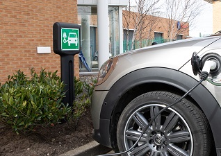 Infomaster™ Bollard with sign carrier for electric car charging station next to silver car