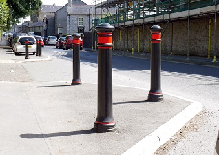 Manchester™ bollard road safety in black with red banding on pavement edge next to road