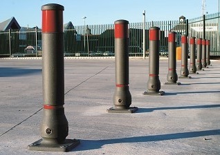Neopolitan™ 150 Bollards in black with red banding in line on car park to prevent vehicle access 