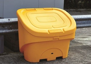 Nestor™ 90 Grit Salt Bin in yellow with snow on lid and operator opening bin on snowy ground
