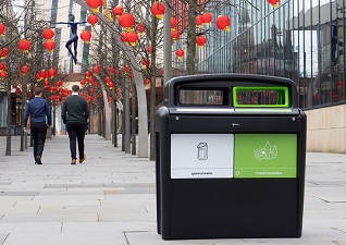 Nexus® Evolution City Duo Recycling Station for general waste and mixed recyclables in black in front of modern walkway with red lanterns in trees