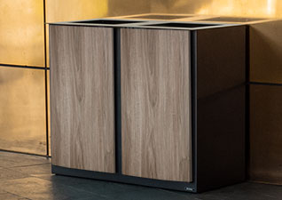 Nexus® Style Recycling Bin in dark teak wood finish against modern copper office wall