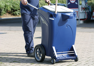 Skipper™ Orderly Barrow in dark blue being pushed by operator next to petrol forecourt